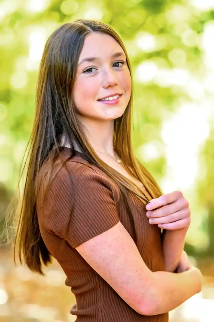 2026 Carl E. Stotz Little League Baseball Scholarship: 14 Winners 2 Ava Gorakh posing outdoors with long brown hair and a brown top during a portrait session