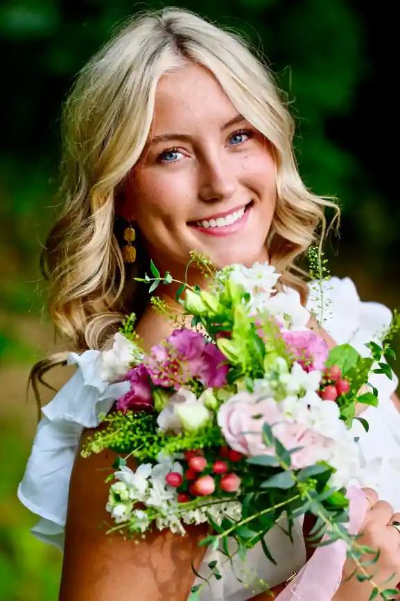 2026 Carl E. Stotz Little League Baseball Scholarship: 14 Winners 15 Ella Moore smiling outdoors while holding a colorful floral bouquet during a portrait session